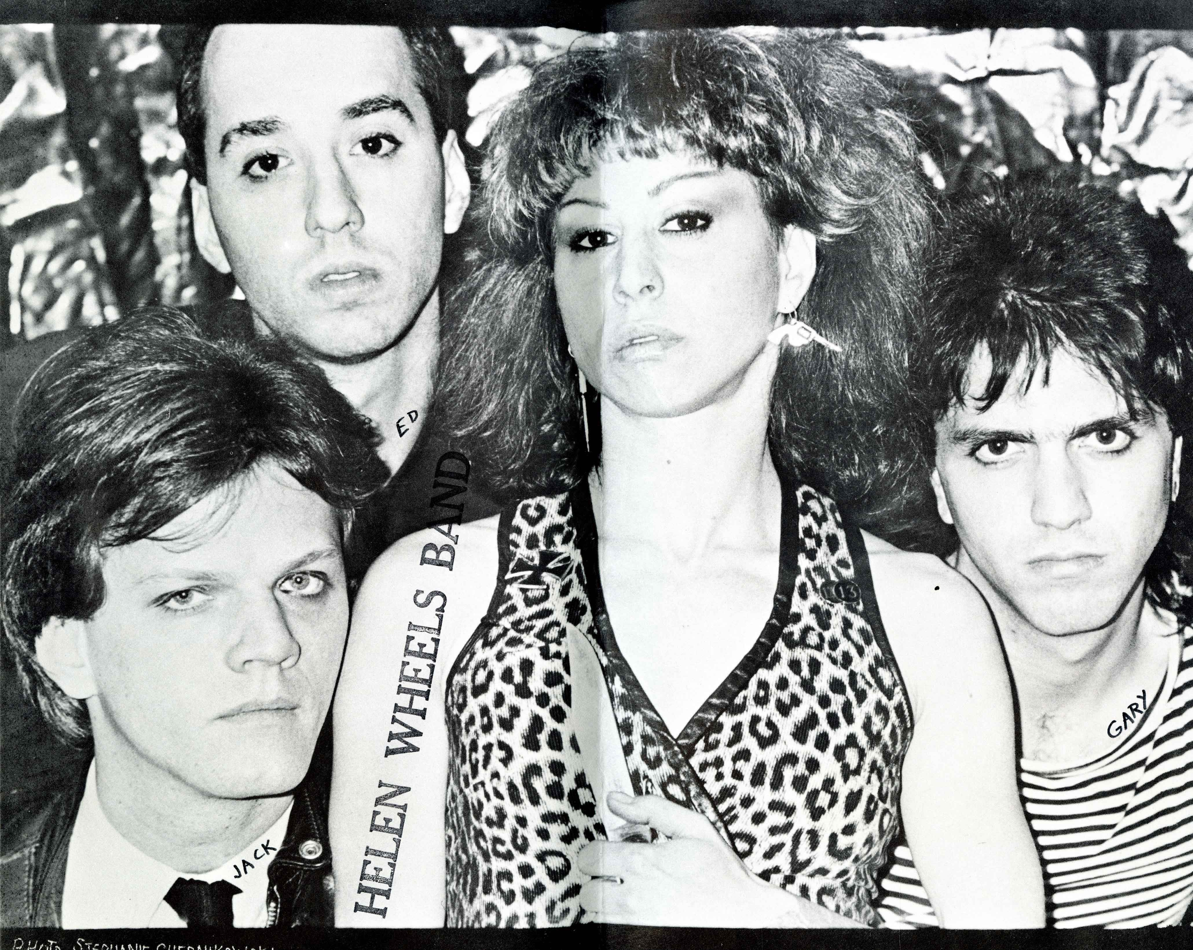 woman in leopard skin vest holding a knife surrounded by 3 men